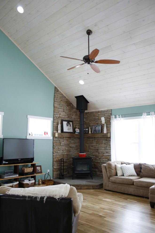 Exemple d'une salle de séjour bord de mer de taille moyenne et ouverte avec un mur bleu, un sol en bois brun, un manteau de cheminée en métal, un téléviseur indépendant et un poêle à bois.