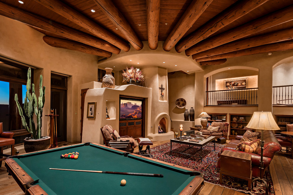Offenes Mediterranes Wohnzimmer mit beiger Wandfarbe, braunem Holzboden, Kamin, verputzter Kaminumrandung und Multimediawand in Phoenix