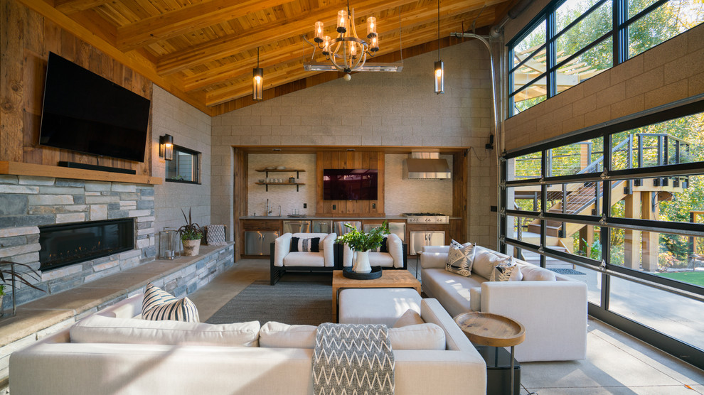 Идея дизайна: открытая гостиная комната среднего размера в современном стиле с серыми стенами, бетонным полом, стандартным камином, фасадом камина из камня, телевизором на стене и серым полом