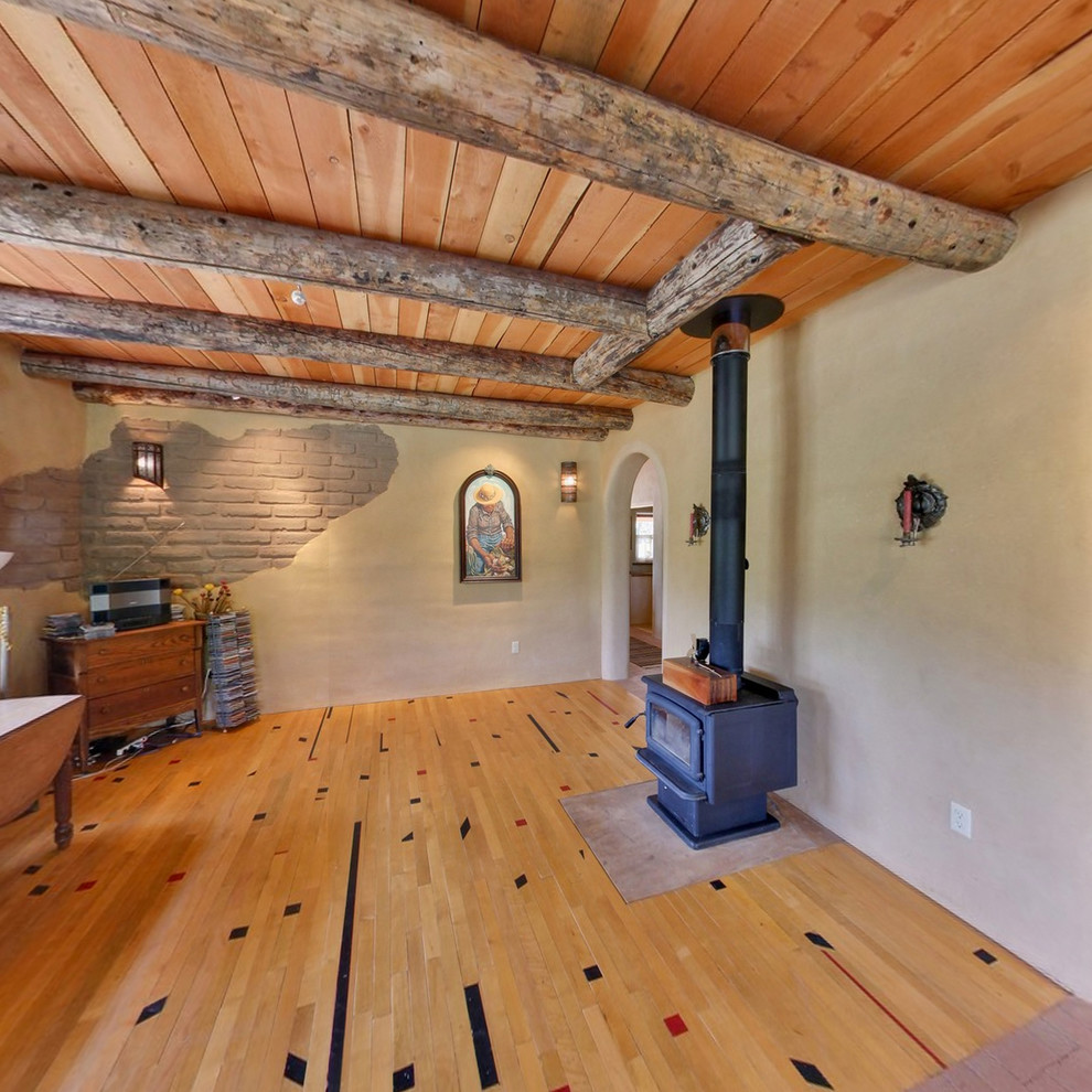 Foto på ett mellanstort amerikanskt allrum med öppen planlösning, med ett musikrum, bruna väggar, ljust trägolv, en öppen vedspis och flerfärgat golv