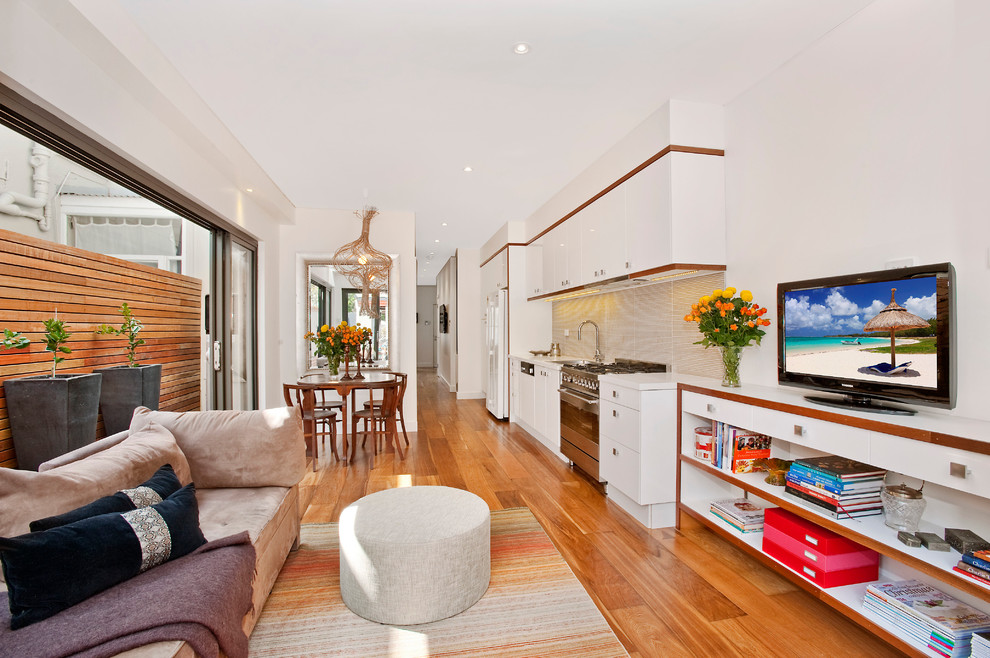 Offenes Modernes Wohnzimmer mit weißer Wandfarbe, braunem Holzboden und freistehendem TV in Sydney