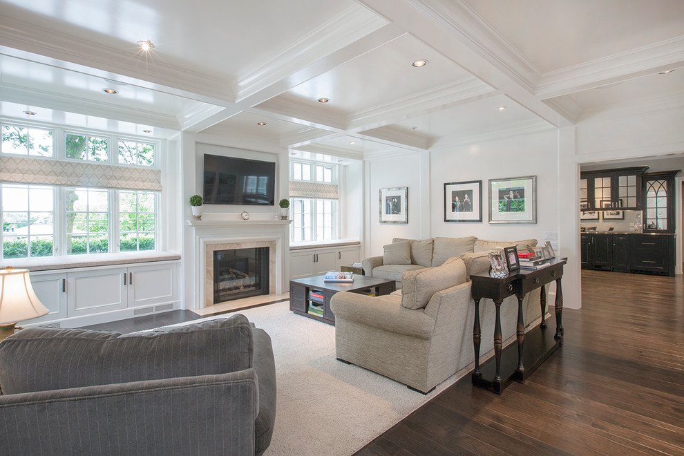 Réalisation d'une grande salle de séjour tradition ouverte avec un mur blanc, parquet foncé, une cheminée standard, un manteau de cheminée en pierre et un téléviseur encastré.