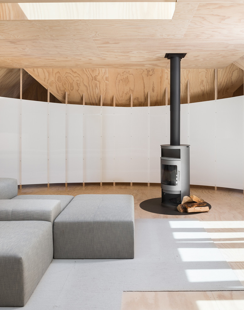 Aménagement d'une salle de séjour mansardée ou avec mezzanine scandinave avec un sol en contreplaqué et un poêle à bois.