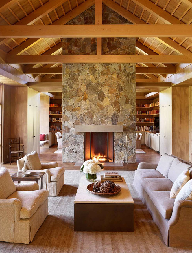 Idée de décoration pour une salle de séjour champêtre ouverte avec un mur marron, un sol en bois brun, une cheminée double-face, un manteau de cheminée en pierre et un sol marron.