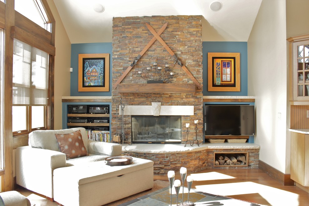 Idée de décoration pour une grande salle de séjour chalet avec un mur beige, un sol en bois brun, une cheminée standard, un manteau de cheminée en pierre et un téléviseur indépendant.