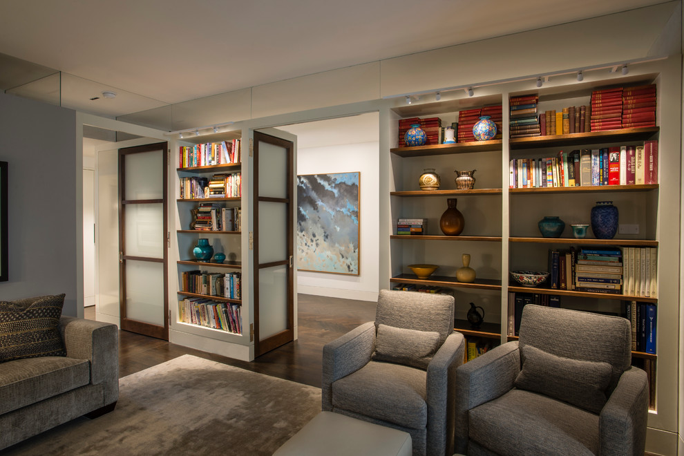 Diseño de sala de estar con biblioteca cerrada contemporánea de tamaño medio sin chimenea con paredes blancas, suelo de madera oscura y televisor colgado en la pared