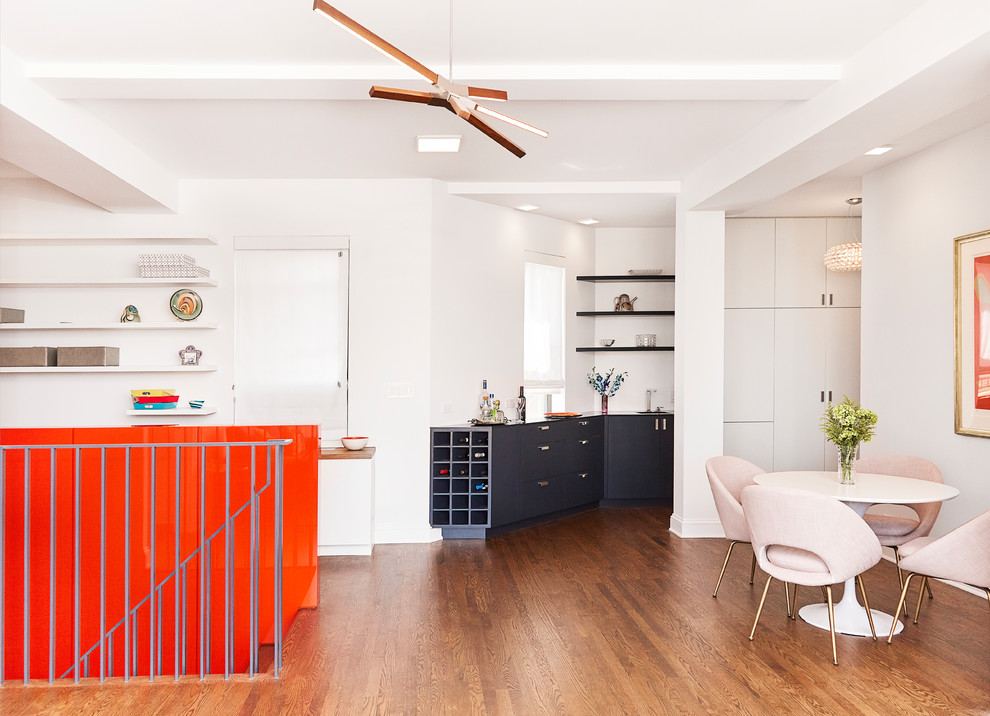 Mittelgroßes, Offenes Modernes Wohnzimmer ohne Kamin mit Hausbar, weißer Wandfarbe, braunem Holzboden, TV-Wand und braunem Boden in New York