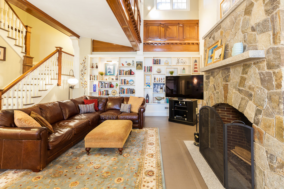 Classic games room in Boston with beige walls, a standard fireplace, a stone fireplace surround and a freestanding tv.
