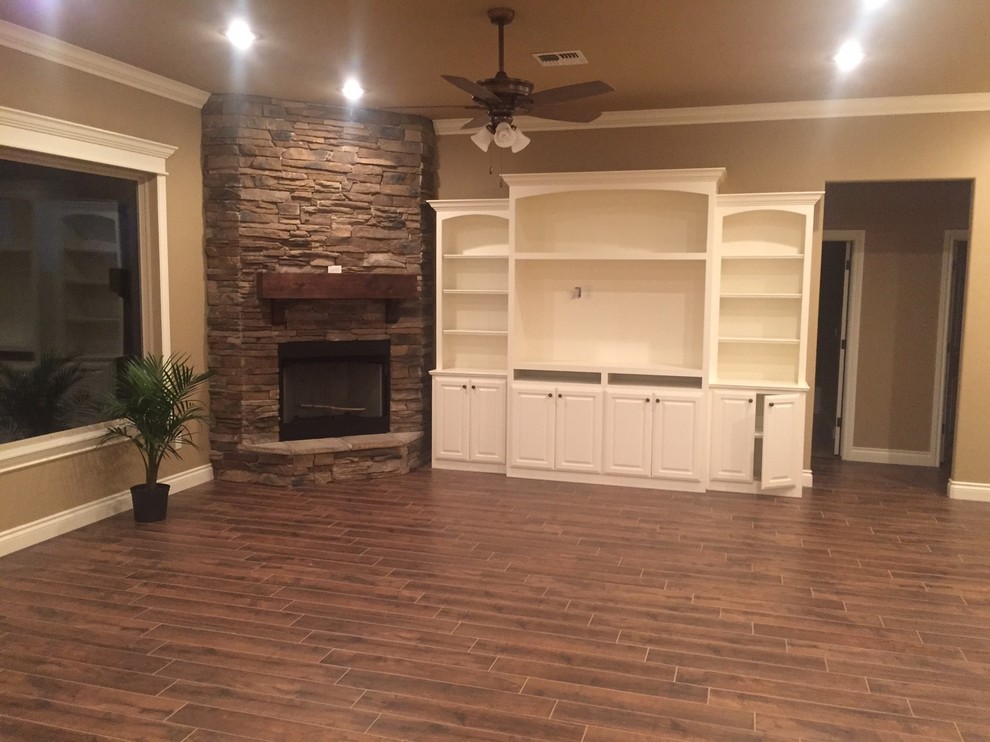 Inspiration for a medium sized rustic open plan games room in Oklahoma City with beige walls, dark hardwood flooring, a corner fireplace, a stone fireplace surround and a built-in media unit.