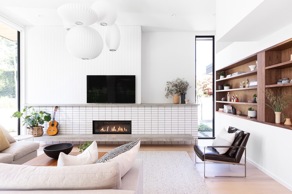 Bild på ett minimalistiskt allrum med öppen planlösning, med ett musikrum, vita väggar, ljust trägolv, en bred öppen spis, en spiselkrans i trä och en väggmonterad TV