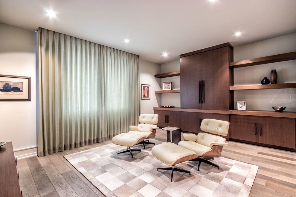 Идея дизайна: гостиная комната в современном стиле с с книжными шкафами и полками, бежевыми стенами, светлым паркетным полом и телевизором на стене