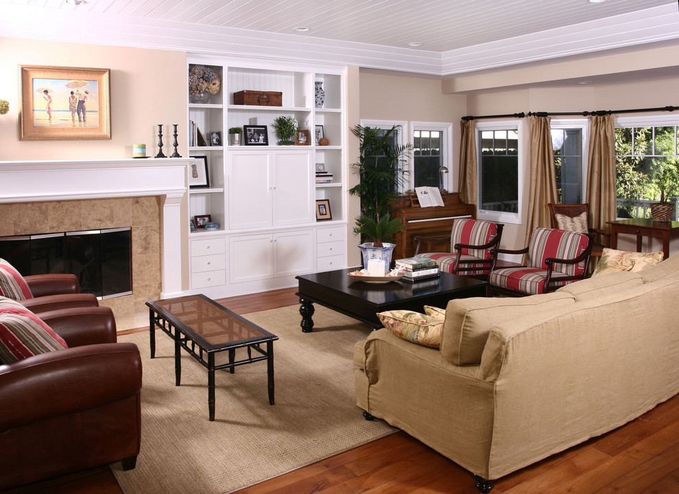 Klassisches Wohnzimmer mit beiger Wandfarbe, braunem Holzboden, Kamin und verstecktem TV in Orange County