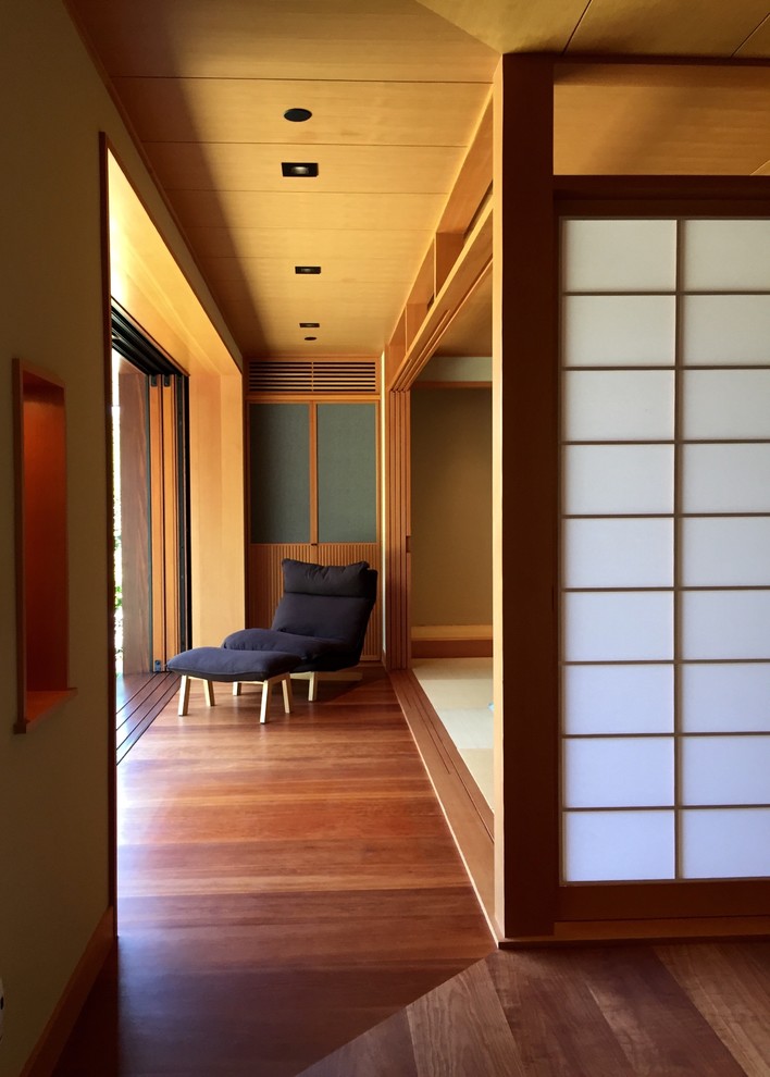 Ejemplo de sala de estar cerrada asiática grande sin chimenea con paredes beige, suelo de madera en tonos medios, televisor independiente y suelo marrón