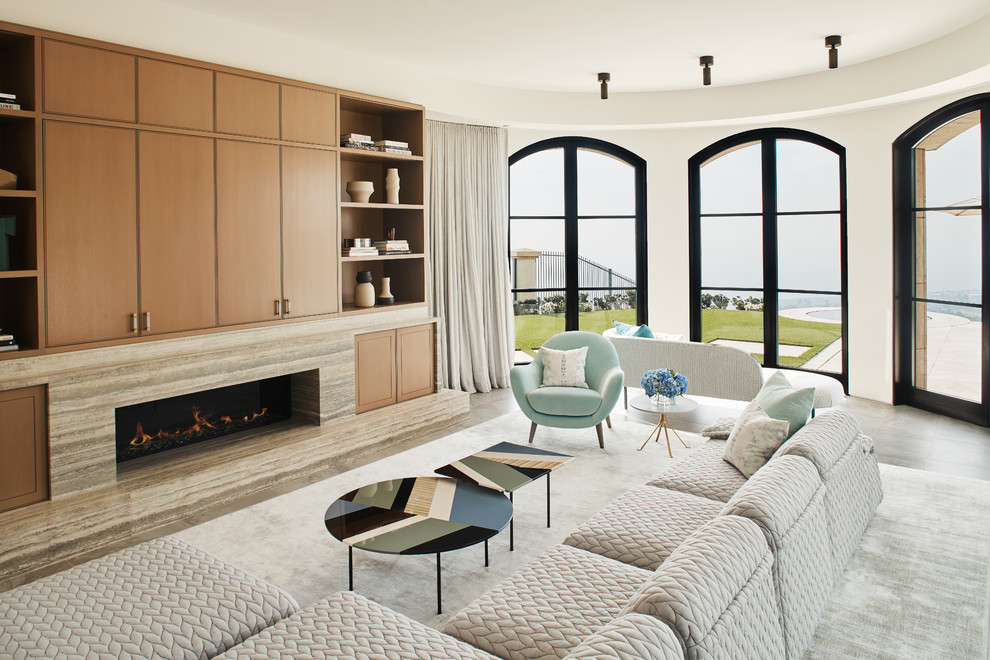 Modelo de sala de estar actual con paredes blancas, chimenea lineal, marco de chimenea de piedra y televisor retractable