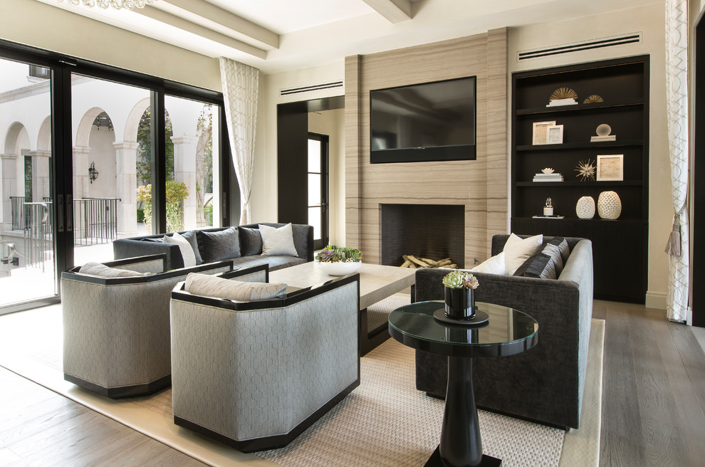 Example of a tuscan medium tone wood floor and gray floor family room design in Orange County with a standard fireplace, a wall-mounted tv and white walls