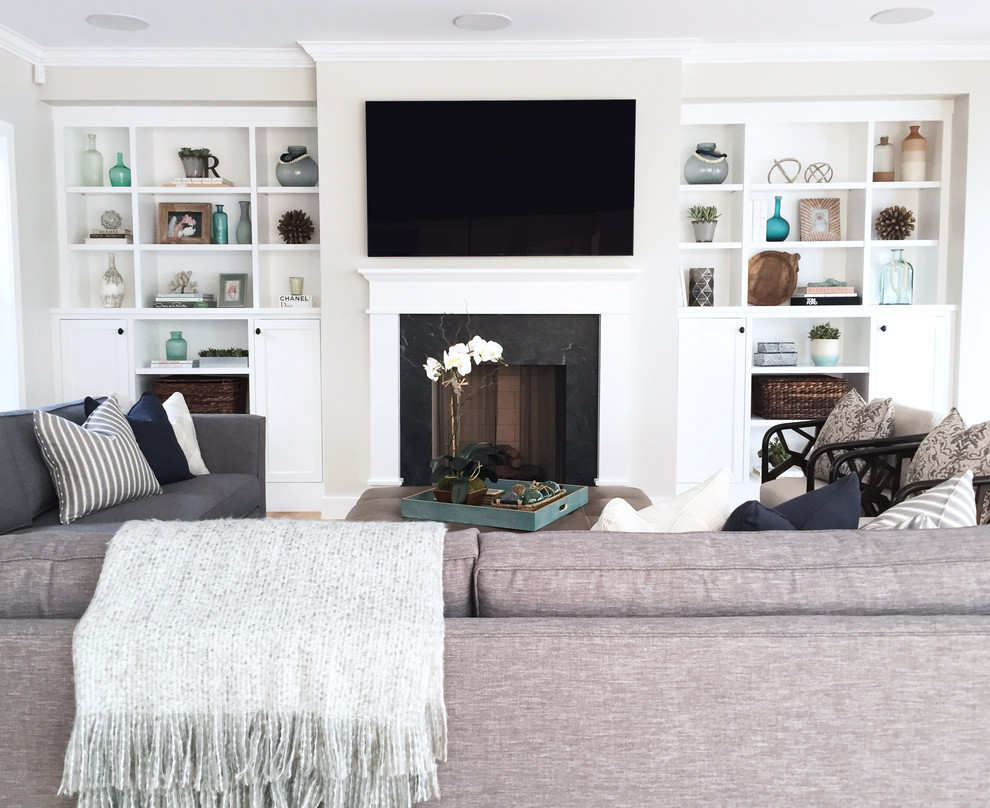 Großes, Offenes Country Wohnzimmer mit weißer Wandfarbe, hellem Holzboden, Kamin, Kaminumrandung aus Stein und TV-Wand in Orange County