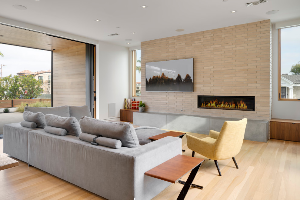 Стильный дизайн: большая открытая гостиная комната в современном стиле с светлым паркетным полом, горизонтальным камином и фасадом камина из кирпича - последний тренд