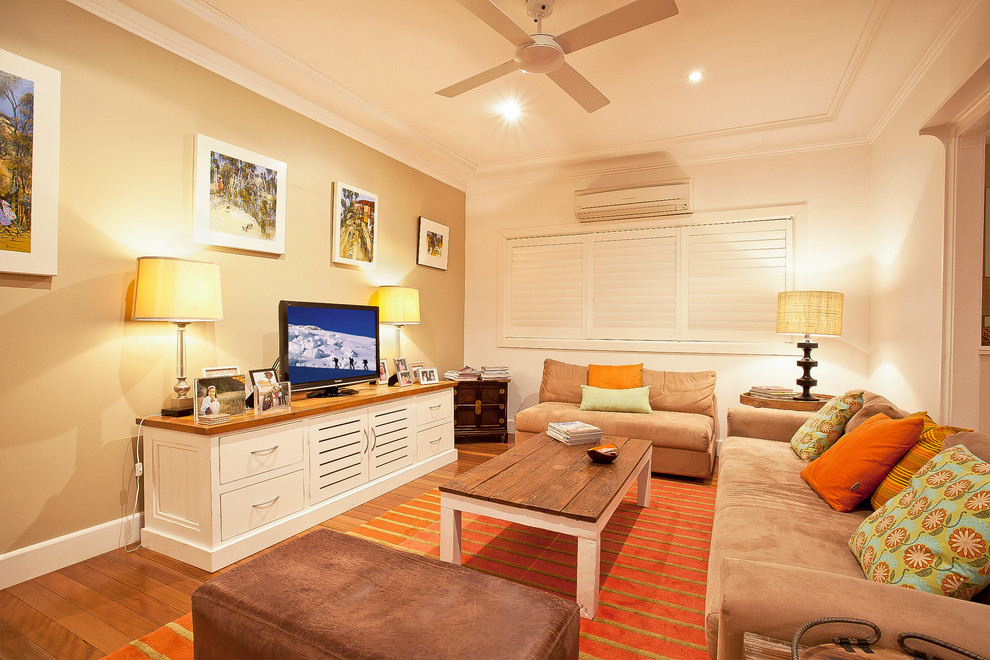 Inspiration pour une salle de séjour traditionnelle avec un mur beige, un sol en bois brun et un téléviseur indépendant.
