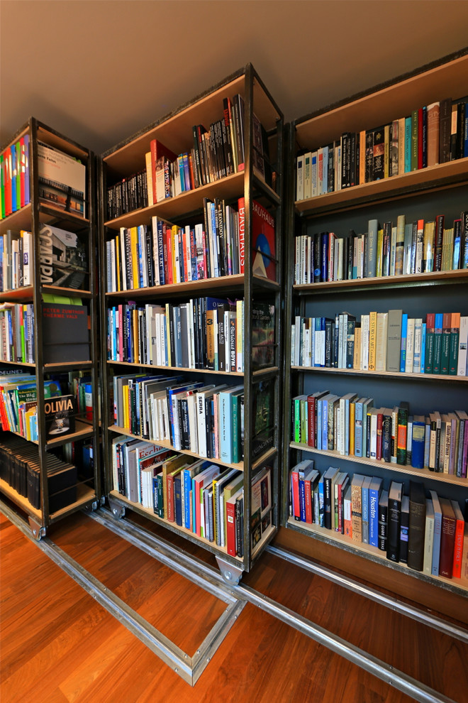 Bild på ett litet funkis allrum, med ett bibliotek och mellanmörkt trägolv