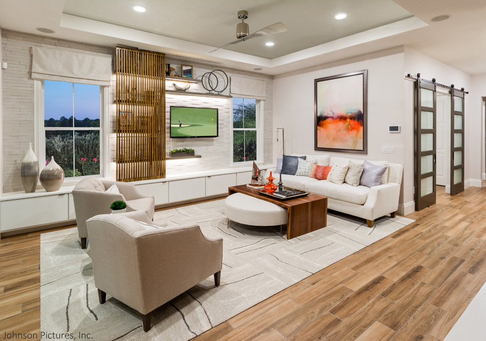 Modelo de sala de estar abierta clásica renovada con paredes blancas, suelo de baldosas de porcelana y televisor colgado en la pared