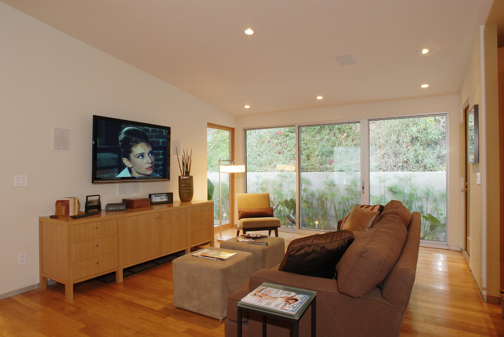 Mid-sized open concept light wood floor family room photo in Los Angeles with green walls, a standard fireplace, a plaster fireplace and a wall-mounted tv