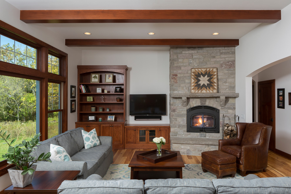 Cette photo montre une salle de séjour craftsman ouverte avec un mur blanc, une cheminée d'angle, un manteau de cheminée en pierre, un sol marron, parquet clair et un téléviseur fixé au mur.