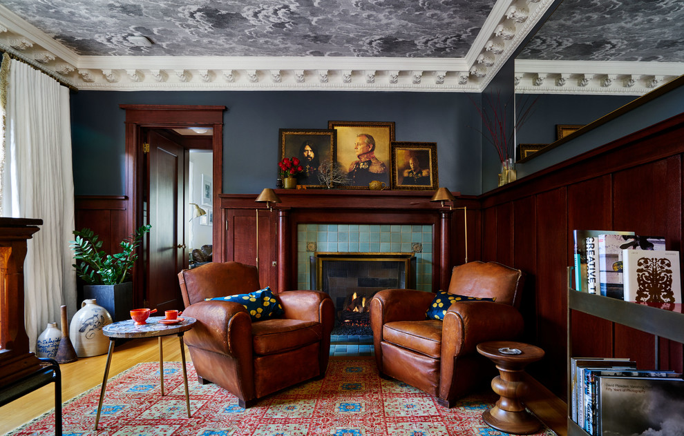 Imagen de sala de estar con biblioteca tradicional con todas las chimeneas, marco de chimenea de baldosas y/o azulejos, paredes grises, suelo de madera en tonos medios y suelo marrón