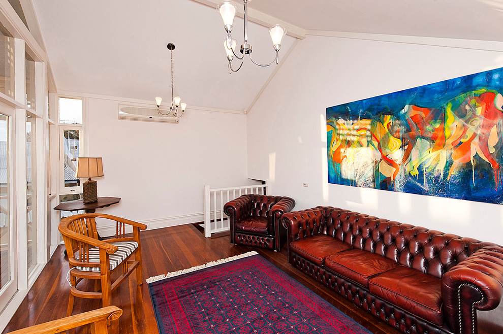 Cette photo montre une salle de séjour mansardée ou avec mezzanine éclectique avec un mur blanc et parquet foncé.