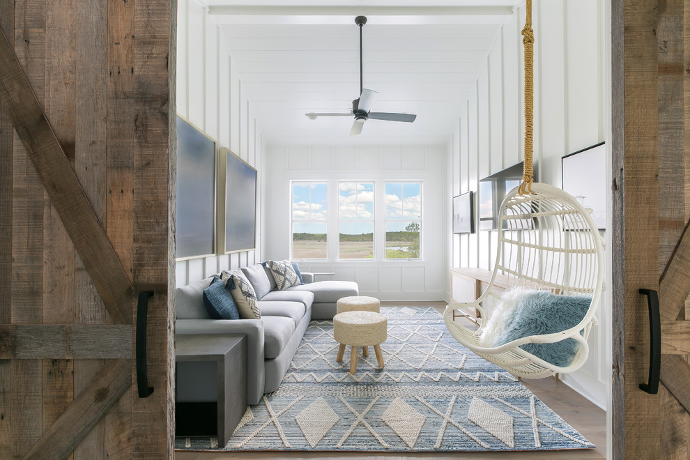 Immagine di un soggiorno stile marinaro di medie dimensioni e chiuso con pareti bianche, pavimento in legno massello medio, pavimento marrone, nessun camino e TV a parete