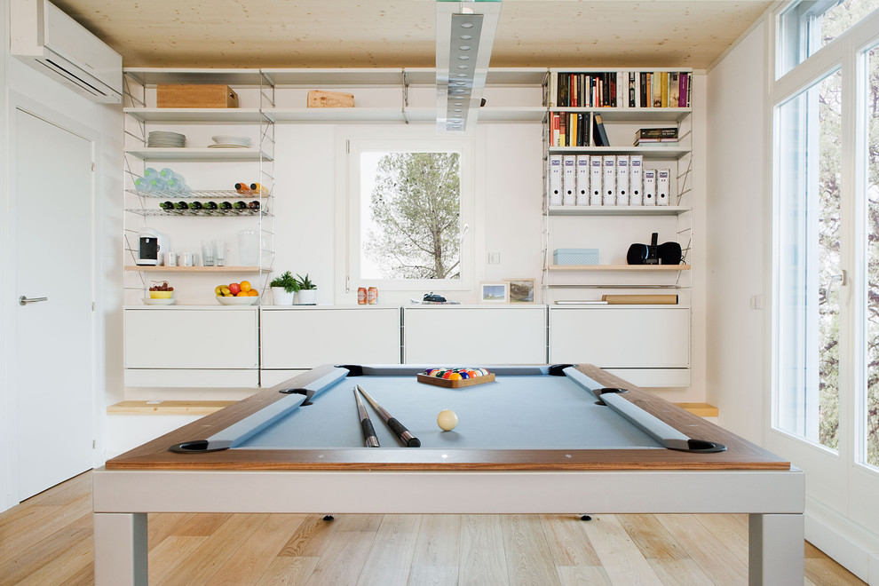 This is an example of a medium sized contemporary enclosed games room in Barcelona with white walls, light hardwood flooring, no fireplace and no tv.