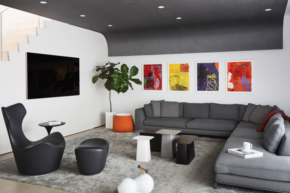 Immagine di un soggiorno contemporaneo con pareti bianche, parquet chiaro e TV a parete