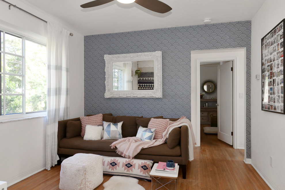 Пример оригинального дизайна: маленькая открытая гостиная комната в стиле фьюжн с розовыми стенами, светлым паркетным полом, телевизором на стене и коричневым полом без камина для на участке и в саду