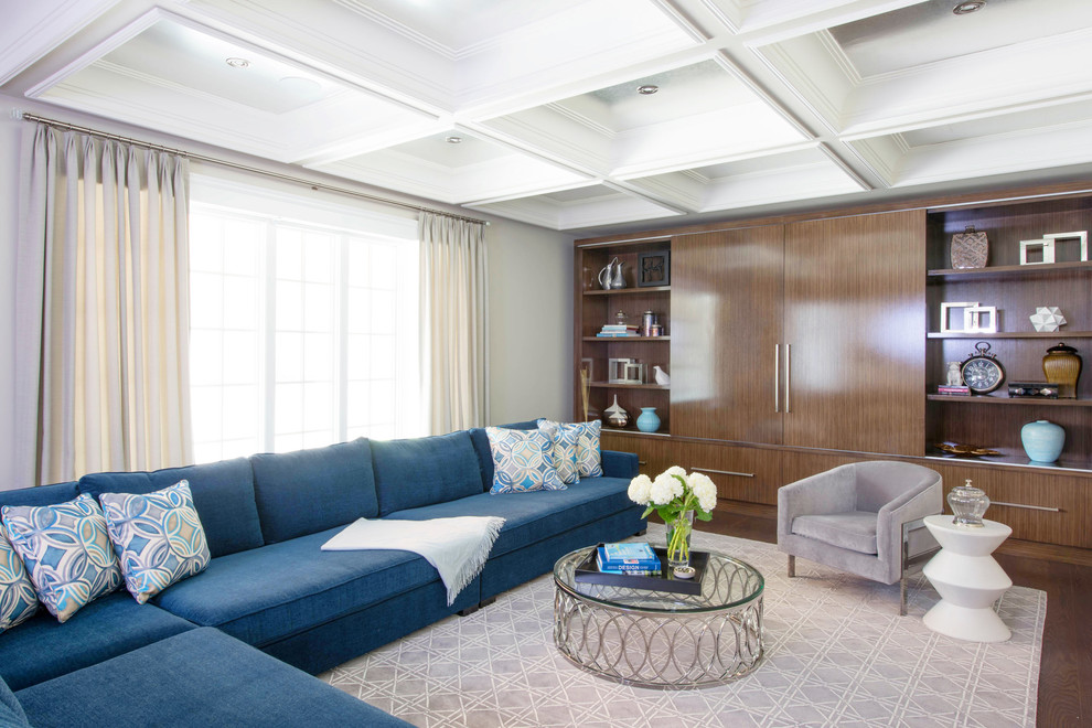 Modelo de sala de estar contemporánea sin chimenea con paredes grises, suelo de madera oscura y televisor retractable