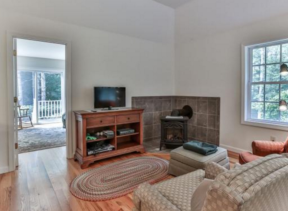 Mittelgroßes, Abgetrenntes Klassisches Wohnzimmer mit weißer Wandfarbe, dunklem Holzboden, Kaminofen, gefliester Kaminumrandung und freistehendem TV in Orange County