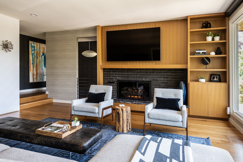 Offenes Retro Wohnzimmer mit hellem Holzboden, Gaskamin, Kaminumrandung aus Backstein und Multimediawand in Seattle