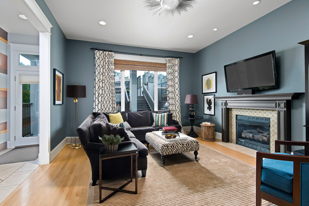 На фото: гостиная комната в стиле неоклассика (современная классика) с синими стенами, светлым паркетным полом, стандартным камином, фасадом камина из плитки и телевизором на стене с