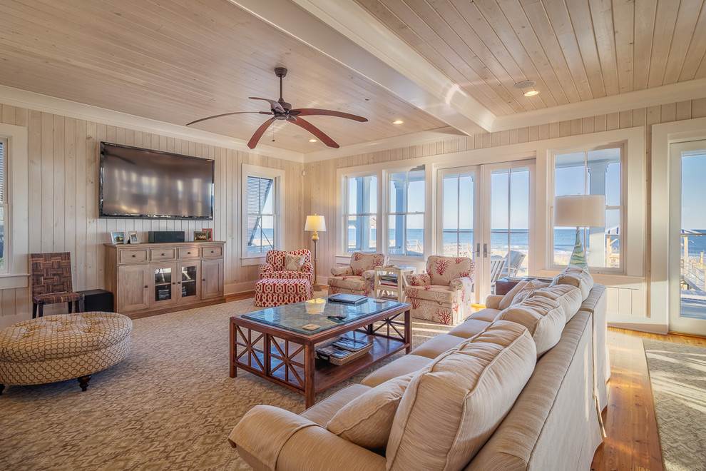 Foto di un soggiorno stile marino aperto con pareti beige, pavimento in legno massello medio, TV a parete e tappeto