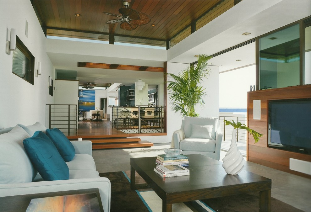 Immagine di un grande soggiorno stile marino aperto con pareti bianche, pavimento in cemento e TV a parete