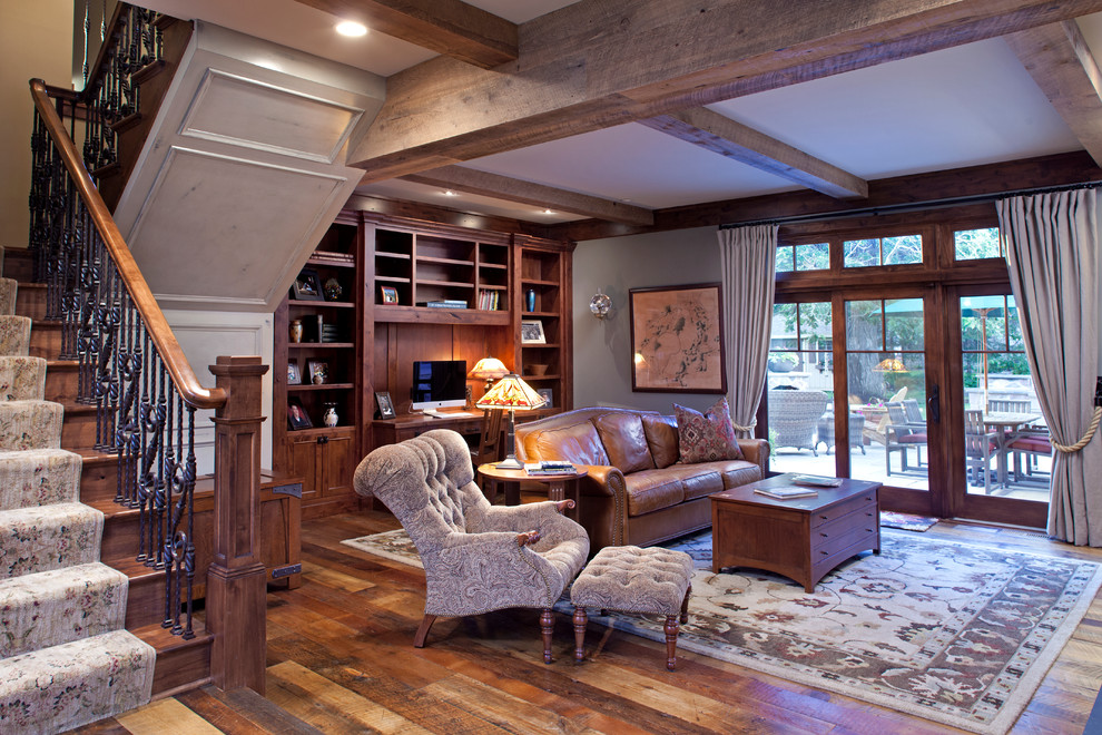 Imagen de sala de estar cerrada grande con suelo de madera en tonos medios, todas las chimeneas, marco de chimenea de piedra y pared multimedia