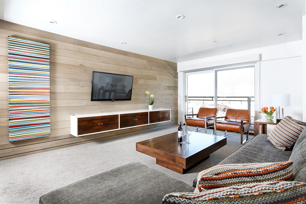 На фото: большая открытая гостиная комната в современном стиле с белыми стенами, ковровым покрытием, телевизором на стене и серым полом без камина