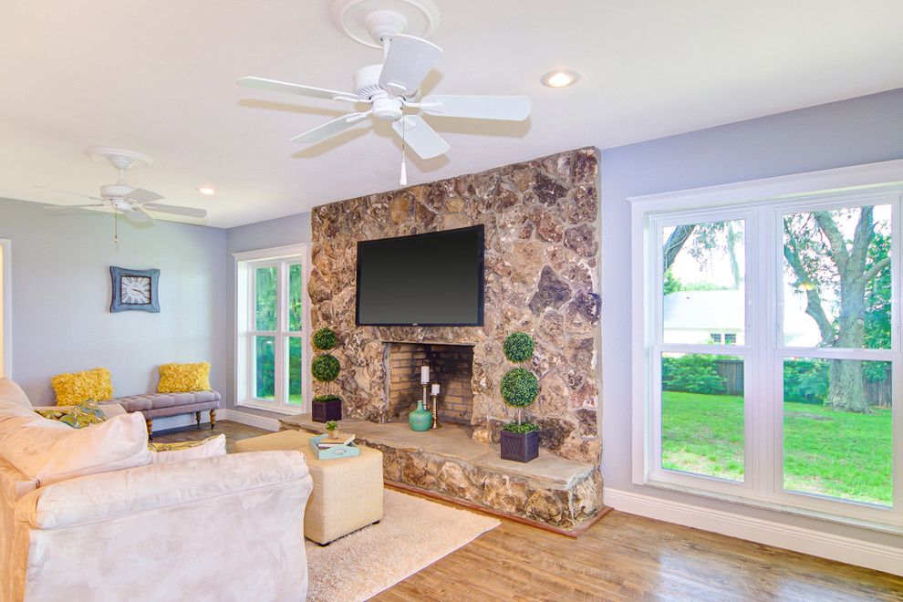 Offenes Retro Wohnzimmer mit blauer Wandfarbe, braunem Holzboden, Kamin, Kaminumrandung aus Stein, TV-Wand und braunem Boden in Orlando