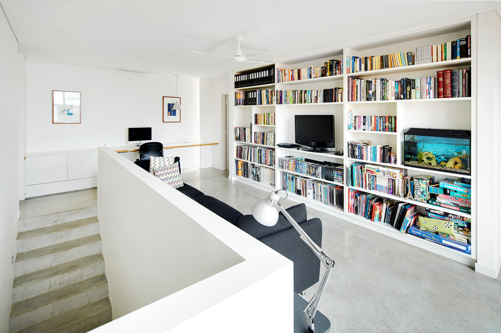 Imagen de sala de estar tipo loft nórdica con paredes blancas, suelo de cemento y televisor independiente