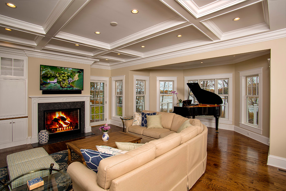 Ejemplo de sala de estar abierta tradicional grande con paredes beige, suelo de madera en tonos medios, todas las chimeneas y marco de chimenea de madera