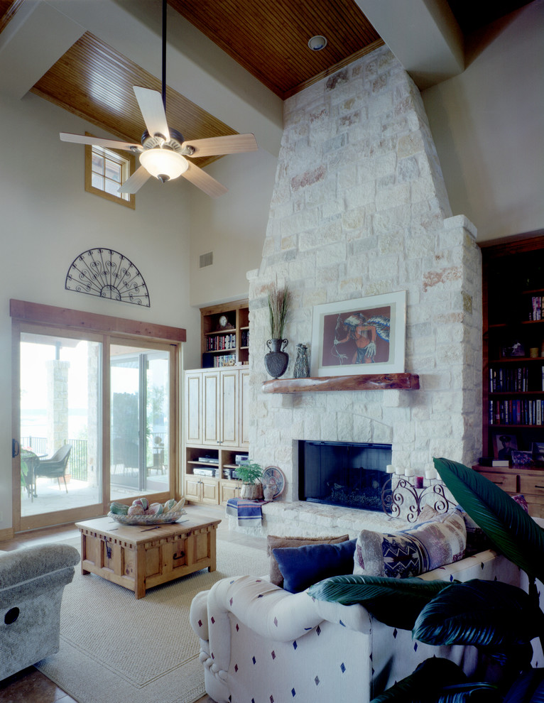 Imagen de sala de estar abierta de estilo de casa de campo grande con paredes blancas, todas las chimeneas, marco de chimenea de piedra y televisor retractable