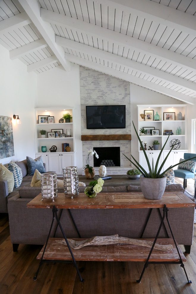 Großes, Offenes Country Wohnzimmer mit Kamin, Kaminumrandung aus Backstein, TV-Wand und braunem Holzboden in Orange County