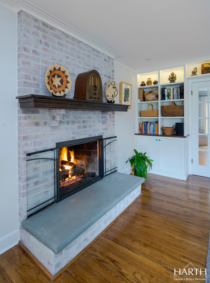 Inspiration for a medium sized classic open plan games room in Philadelphia with white walls, medium hardwood flooring, a standard fireplace, a brick fireplace surround, a wall mounted tv and brown floors.