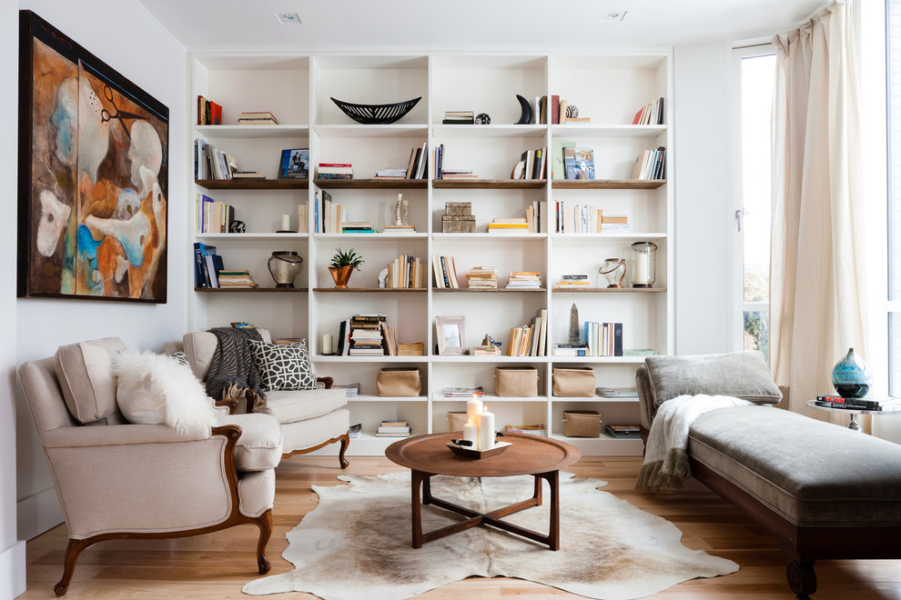 Exemple d'une salle de séjour tendance avec une bibliothèque ou un coin lecture, un mur blanc, un sol en bois brun, aucune cheminée et aucun téléviseur.