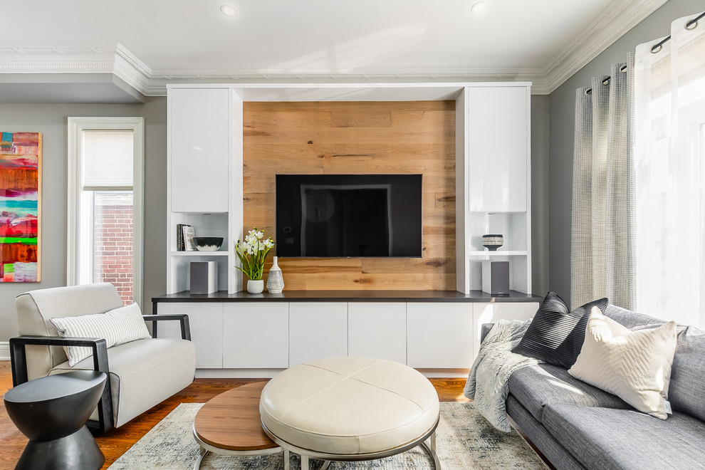 Offenes Modernes Wohnzimmer ohne Kamin mit grauer Wandfarbe, braunem Holzboden und TV-Wand in Toronto