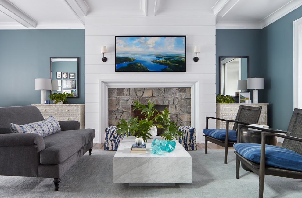 Diseño de sala de estar costera con paredes azules, todas las chimeneas, marco de chimenea de piedra y televisor colgado en la pared