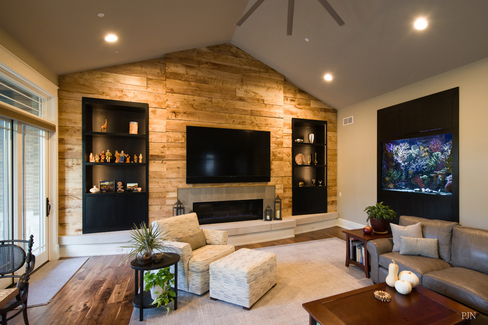 Diseño de sala de estar abierta grande con paredes multicolor, suelo de madera en tonos medios, chimenea lineal, marco de chimenea de piedra, televisor colgado en la pared y suelo marrón